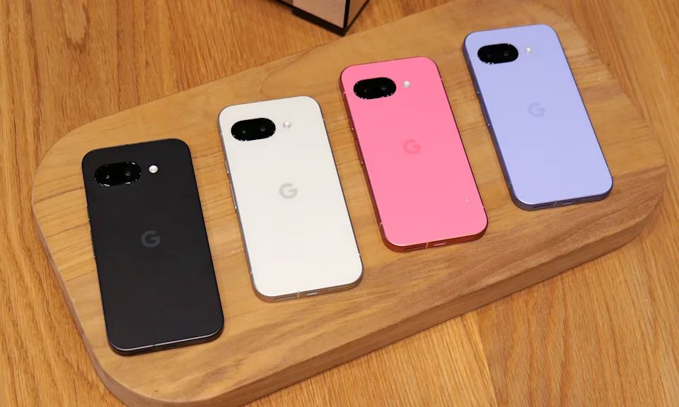 A row of four pixel 9a phones on a table.